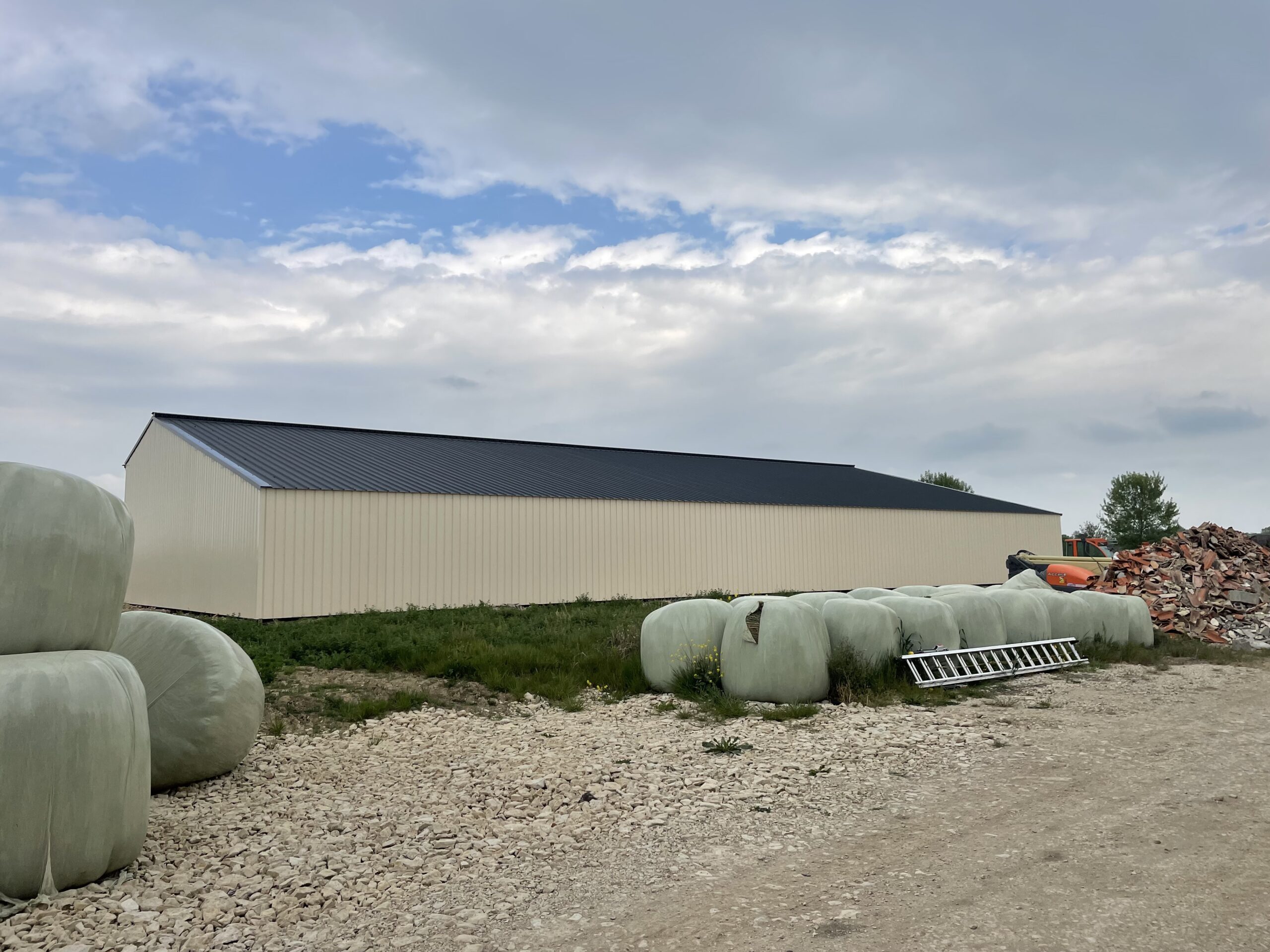 Hangars neuf avec panneaux solaires sur le toit et des bottes de pailles devants